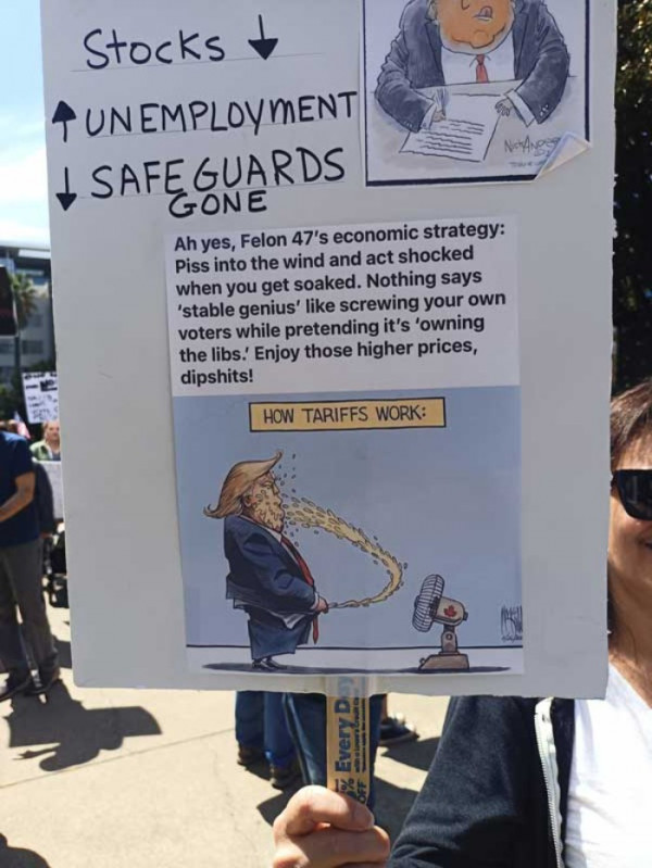 Protestor's sign showing Trump Peeing into a fan and getting it all over his face
